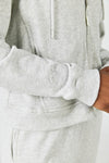 Close-up of cropped zip hoodie and straight leg sweatpant set in grey with embroidery logo, side pockets, adjustable drawstring, and elastic waistband.